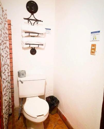 a bathroom with a toilet and towels on the wall at Hotel Olimpia Centro Histórico in Monclova