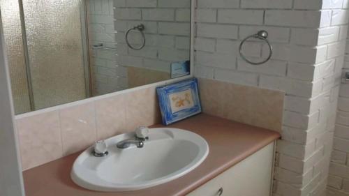 a white sink in a bathroom with a mirror at Solaris Court Unit 5 in Caloundra