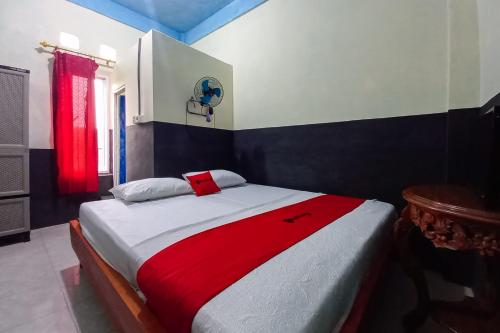 a bedroom with a large bed with a red blanket at RedDoorz Syariah at Penginapan Queen Sungai Penuh in Sungaitutung