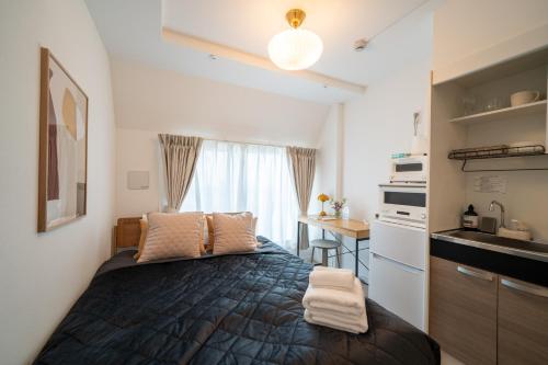 a small bedroom with a bed and a kitchen at Ken's Place Omotesando in Tokyo