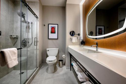 a bathroom with a toilet and a sink and a shower at Hotel Indigo Baton Rouge Downtown by IHG in Baton Rouge
