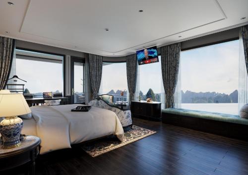 a bedroom with a large bed and large windows at Majesty Luxury Prime Cruise by Premier Group in Ha Long