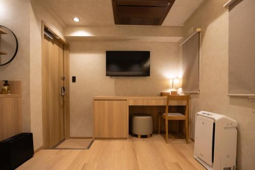 a room with a desk and a television on the wall at Hotel Paul House in Tokyo