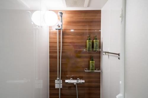 a bathroom with a shower with bottles on the wall at Ken's Place Omotesando in Tokyo