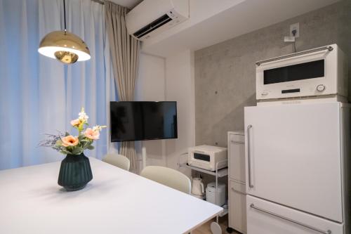 a room with a white table with a vase of flowers at Ken's Place Omotesando in Tokyo