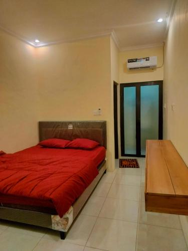 a bedroom with a red bed and a window at Sulfat Indah home stay syariah in Ngadipuro