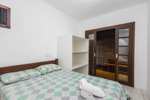 a bedroom with a bed with a green and white blanket at 5 Pessoas | Praia Armação | Beto Carrero in São Lídio