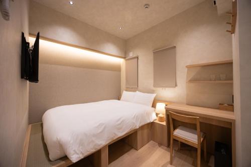 a small bedroom with a white bed and a desk at Hotel Paul House in Tokyo