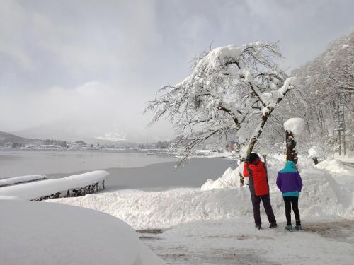 two people standing next to a tree covered in snow at Hotel Tae Windsor in Myoko