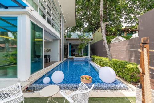 a swimming pool with white chairs and a house at 6BR Homestay KL Pool Villa - 4KM To KLCC by Verano in Ampang