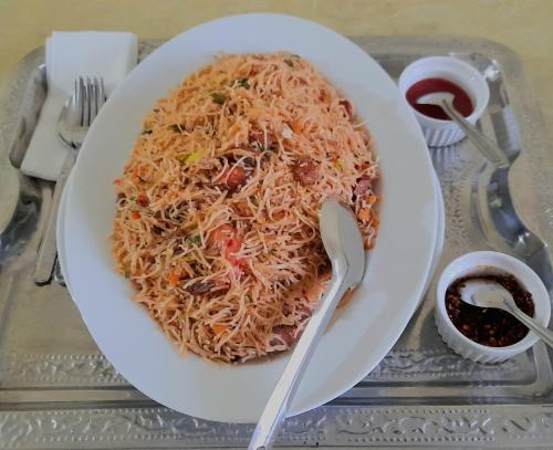 a plate of food with noodles on a table at Madara Hotel in Horana