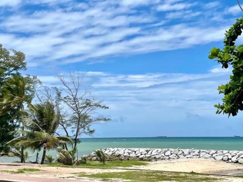 a beach with a rock wall and the ocean at Baan Lita Rayong บ้านลิตา in Ban Noen Phra