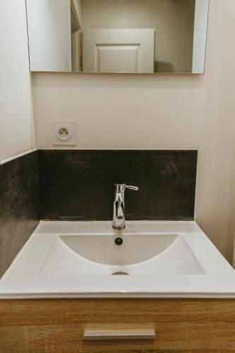 un lavabo blanc dans une salle de bain avec un miroir dans l'établissement Le Granier, une évasion aux pieds des Bauges 0, à Leysse