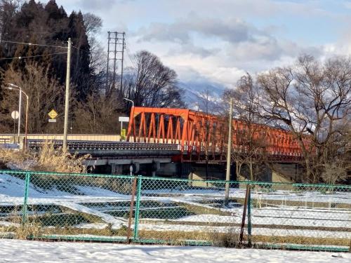 an orange train crossing a bridge in the snow at Hotel Tae Windsor in Myoko