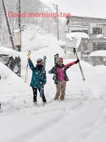 two people are standing in the snow with their skis at Hotel Tae Windsor in Myoko