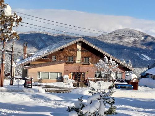 a house covered in snow with mountains in the background at Hotel Tae Windsor in Myoko