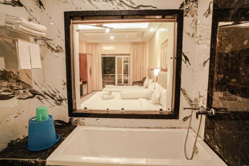 La salle de bains est pourvue d'une baignoire et offre une vue sur une chambre. dans l'établissement Prasant Beach Resort Mandarmani, à Mandarmoni