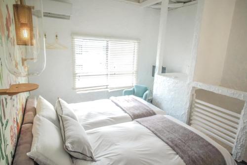 a bedroom with a bed with white sheets and a window at Maison De Vacances Hayama in Hayama