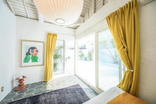 a bedroom with yellow curtains and a large window at Maison De Vacances Hayama in Hayama