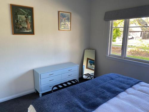 a bedroom with a bed and a dresser and a mirror at Home Away From Home on Phoenix in Palmerston North