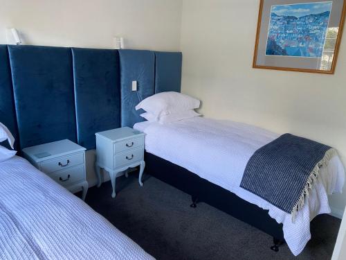a bedroom with two beds and a blue headboard at Home Away From Home on Phoenix in Palmerston North