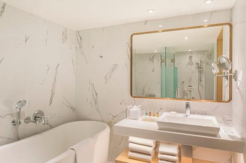 a bathroom with a tub and a sink and a mirror at Holiday Inn Golden Mile by IHG in Hong Kong