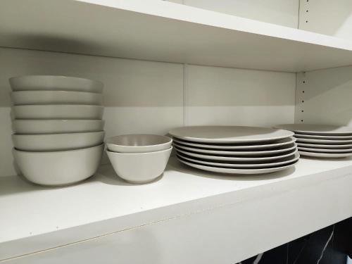 a white shelf with plates and bowls on it at Charming & Compact Retreat in St. Albert