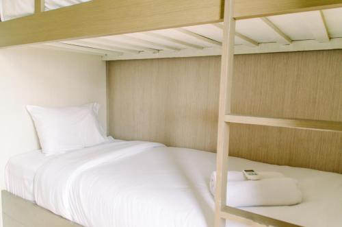 a bedroom with a bunk bed with white sheets at Simply and Cozy Pool View 2BR at Great Western Apartment By Travelio in Pumpangsineng