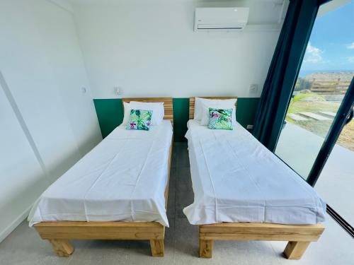 two beds in a room with a window at Villa SKY 4 Chambres - Vue sur le Diamant in Morne Blanc