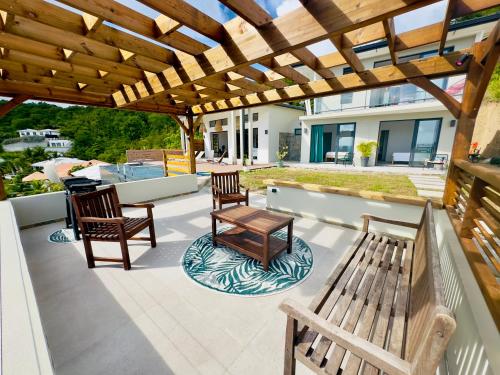 a patio with two benches and a table at Villa SKY 4 Chambres - Vue sur le Diamant in Morne Blanc