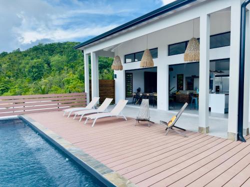 a house with a deck with chairs and a swimming pool at Villa SKY 4 Chambres - Vue sur le Diamant in Morne Blanc