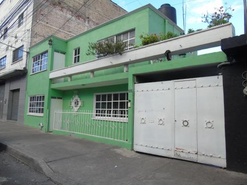 a green and white building with a garage at Tokali, GuestHouse in Mexico City