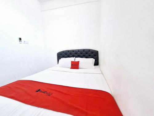 a bed in a white room with a red blanket at RedDoorz near Stasiun Kediri in Kediri