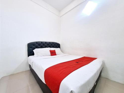 a white room with a bed with a red blanket at RedDoorz near Stasiun Kediri in Kediri
