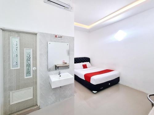 a bedroom with a bed and a sink and a mirror at RedDoorz near Stasiun Kediri in Kediri