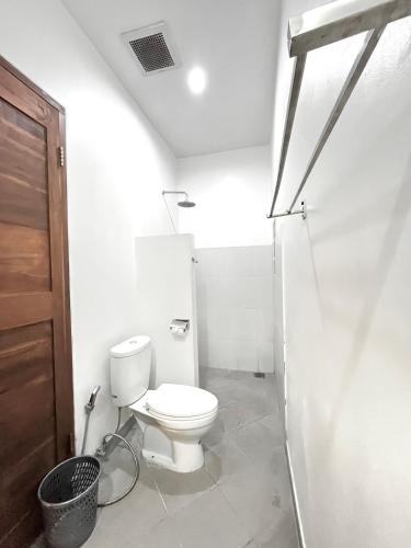 a white bathroom with a toilet and a shower at Pererenan nengah guest house canggu in Canggu