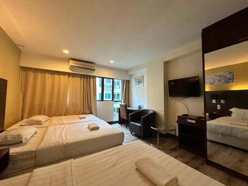 a hotel room with two beds and a television at Greenage MingSuite 明绿时代套房 Kota Kinabalu 亚庇市中心 in Kota Kinabalu