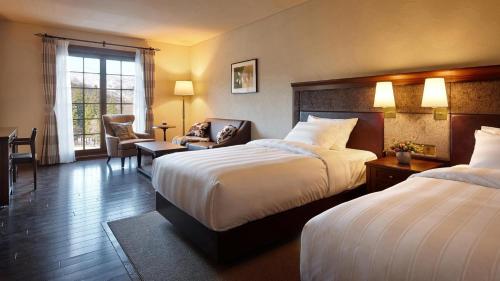 a hotel room with two beds and a chair at Lotte Arai Resort in Myoko