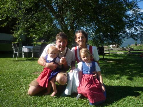a man and a woman and two babies sitting on the grass at Ferienwohnung Peter Egger in Gosau