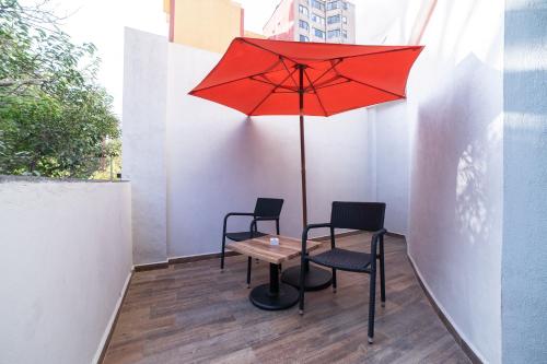 a table with two chairs and a red umbrella at Hotel Círculo Condesa in Mexico City