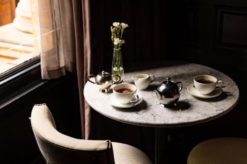 a table with cups of coffee and a vase of flowers at Kimpton Fitzroy London by IHG in London