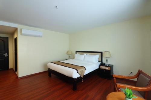 a hotel room with a bed and a chair at Mahasakor Inn in Phnom Penh