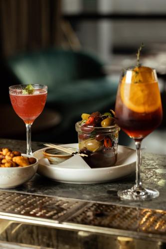 a table with two cocktails and a plate of food at West Hotel Sydney, Curio Collection by Hilton in Sydney