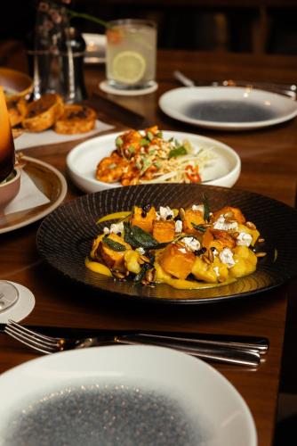 a plate of food on a table with plates of food at West Hotel Sydney, Curio Collection by Hilton in Sydney