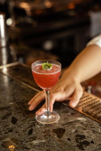 a person holding a cocktail on a counter at West Hotel Sydney, Curio Collection by Hilton in Sydney
