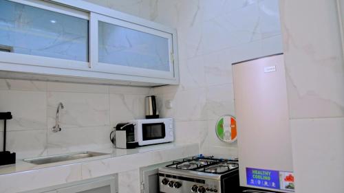 a white kitchen with a stove and a microwave at Locabiss 5, ALMADIES 2 in Rufisque