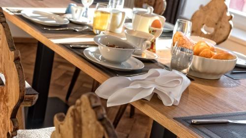 a wooden table topped with cups and plates of food at Niedermairhof in Brunico