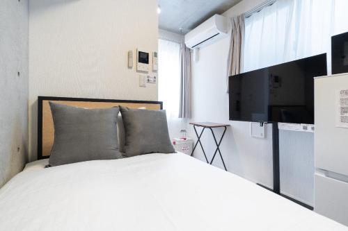 a bedroom with a bed and a flat screen tv at Ferio minamikamata in Tokyo