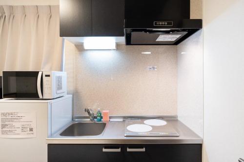 a small kitchen with a sink and a microwave at Ferio minamikamata in Tokyo