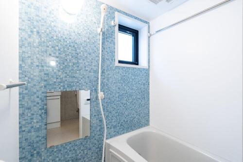 a bathroom with a tub and a shower with blue tiles at Ferio minamikamata in Tokyo